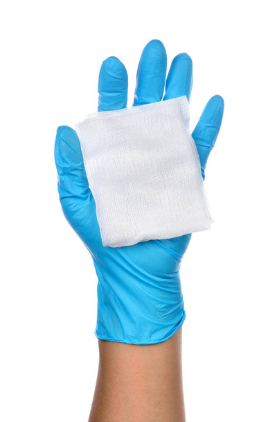 Gazlı bez ile mavi lateks eldiven giymiş bir doktor eller. - Fotoğraf, Görsel