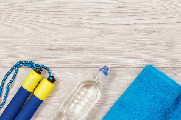 Verschillende hulpmiddelen voor fitness met flesje water in de kamer of sportschool op grijze vloer - Foto, afbeelding