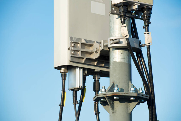Телекомунікаційна вежа з секторними антенами на тлі блакитного неба
 - Фото, зображення