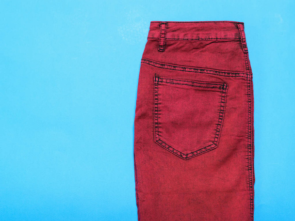 Burgunder Jeansrock auf blauem Hintergrund. modische Jeans-Damenbekleidung. Jeans-Frauenkleidung auf farbigem Hintergrund. - Foto, Bild