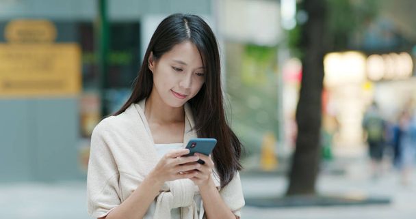 Nő használ mozgatható telefon részére elküldés sms  - Fotó, kép