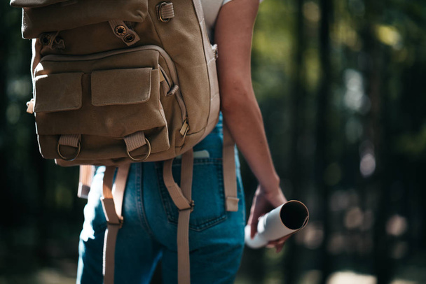 Back view of close-up traveler backpack and cute brave woman traveling alone among forest on outdoor - Foto, Imagem