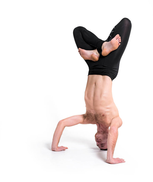 Yoga. Jonge man een oefening doet. Hand staande pose. Yogi master training op stedelijke studio. Guy doen yoga binnenshuis, gezonde levensstijl-concept - Foto, afbeelding