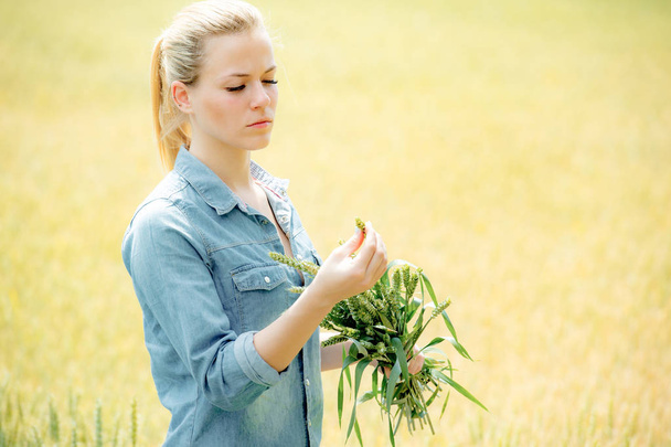 Hezká mladá dívka drží uši pšenice na žlutém poli pšenice - Fotografie, Obrázek