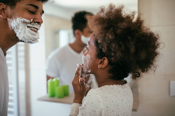 Photo of african american father and daughter having fun with shaving foam in the bathroom. - Φωτογραφία, εικόνα