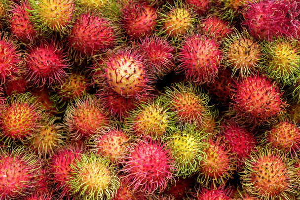 of full frame close up of forty rambutan red hairy circular fruits stacked on top of each other
 - Фото, изображение