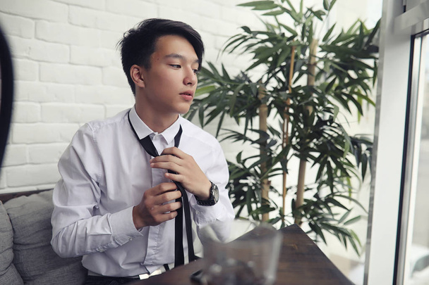 Un joven empresario asiático está esperando a un socio en un café. Bu.
 - Foto, Imagen