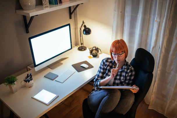 Young hipster making a notes while working in the home office. - 写真・画像