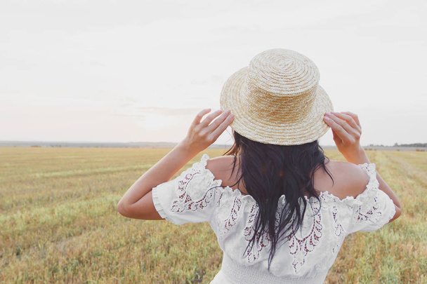 Krásná mladá žena v bílých šatech na pozadí polí, měkké zaostření - Fotografie, Obrázek