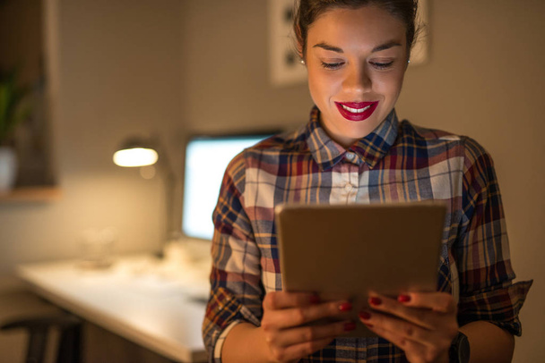 Beautiful casual girl working on a tablet late at night. - Foto, imagen