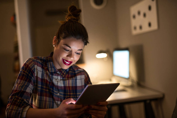 Close up portrait of a young businesswoman working on a digital tablet late at night. - Zdjęcie, obraz
