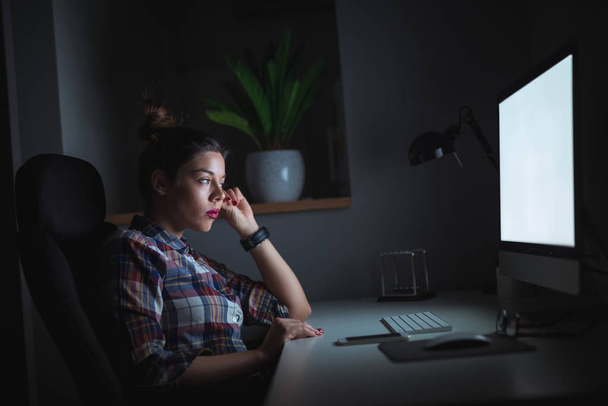 Giovane donna stanca che lavora al computer da casa. Lei è seduta davanti a un computer e pensa al progetto
. - Foto, immagini