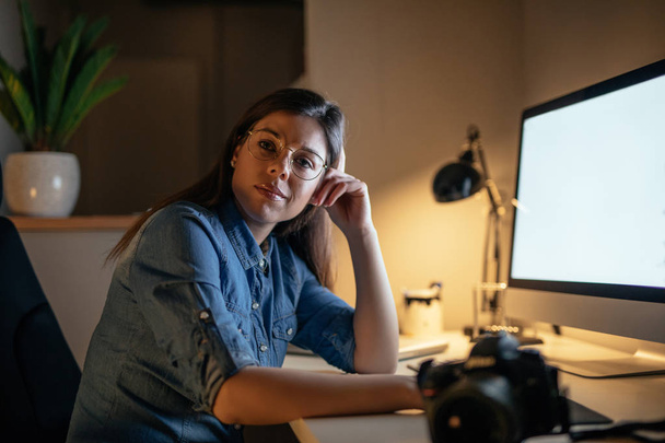 Shot of a young businesswoman wearing glasses and sitting at the computer table. - Фото, зображення