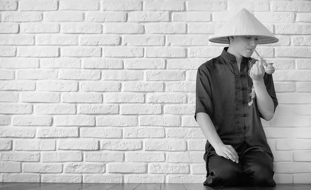 Asian novice on a white brick wall - Zdjęcie, obraz