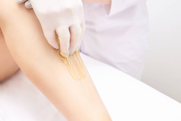 Waxing woman leg. Sugar hair removal. laser service epilation. Salon wax beautician procedure. - Foto, Imagem