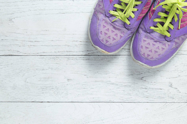 Deporte plano poner zapatos de color púrpura sobre fondo de madera blanca con copyspace para su texto. Concepto estilo de vida saludable y dieta
. - Foto, Imagen