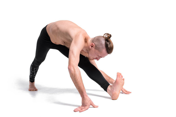 Man in yoga pose doing yoga exercises. Studio shot over white background and white floor - Photo, Image