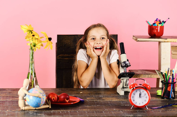 Girl with cheerful face sits at desk. Laboratory and beauty - Фото, зображення