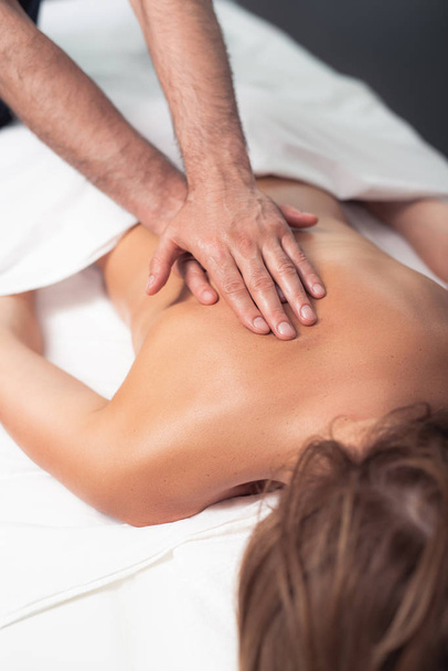 Professional masseur treating women with therapeutic massage - 写真・画像