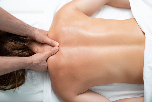 Professional masseur treating lady with therapeutic back and neck massage - Foto, imagen