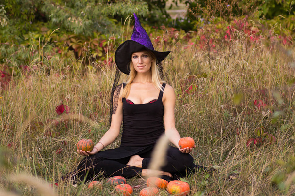 Ragazza in costume di Halloween praticare posizioni yoga con le zucche nelle sue mani
 - Foto, immagini