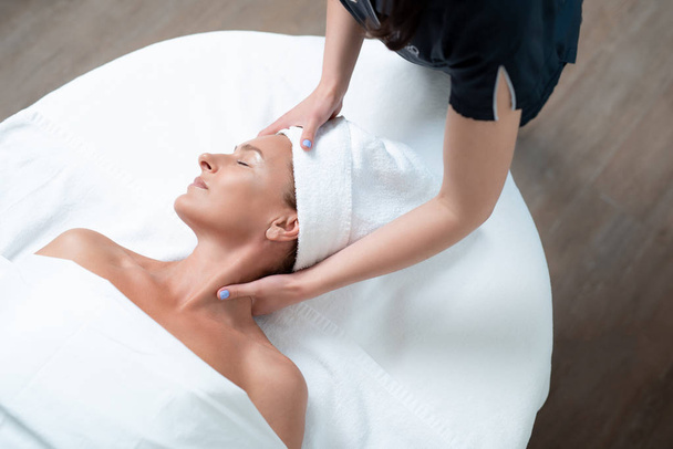 Calm middle aged woman getting face and neck massage at spa salon - Photo, Image