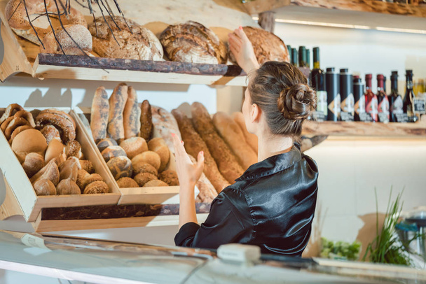 Shop assistant sorting bread to be sold - 写真・画像