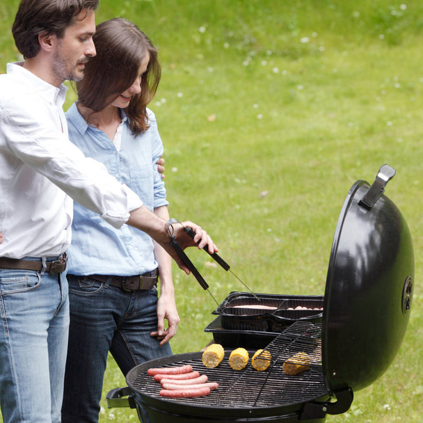 Happy couple cooking food on barbecue - Foto, imagen