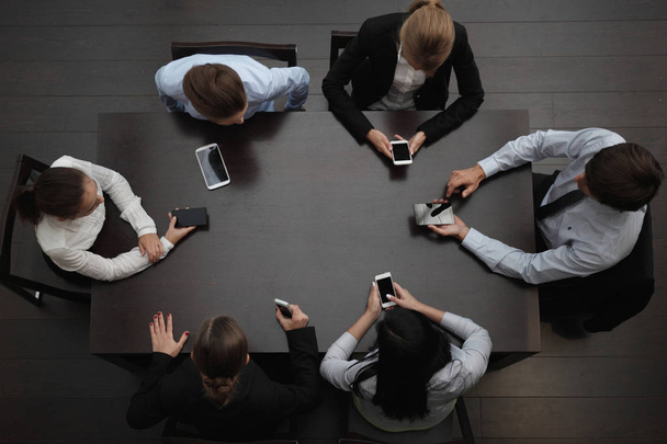Business people with smartphones sitting around the table, top view - Foto, Imagen