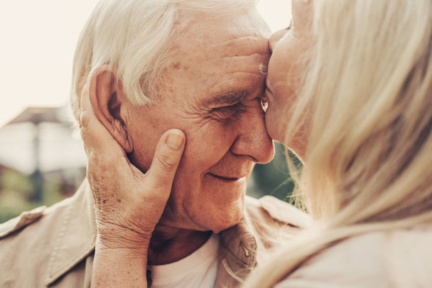 Focus on wrinkled male face kissed by lady - Foto, immagini