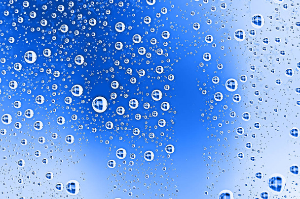 blue wet background, raindrops on window glass, concept of autumn weather - 写真・画像