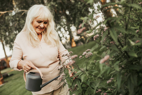Kind silver haired woman acting as gardener - Foto, Imagen