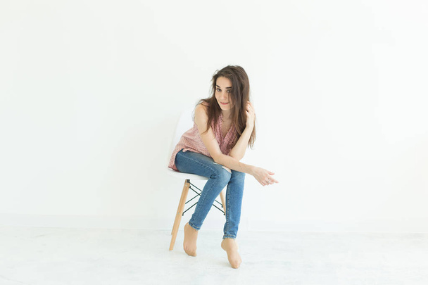 Beautiful brunette student woman sitting on a chair on white background with copy space - Foto, immagini