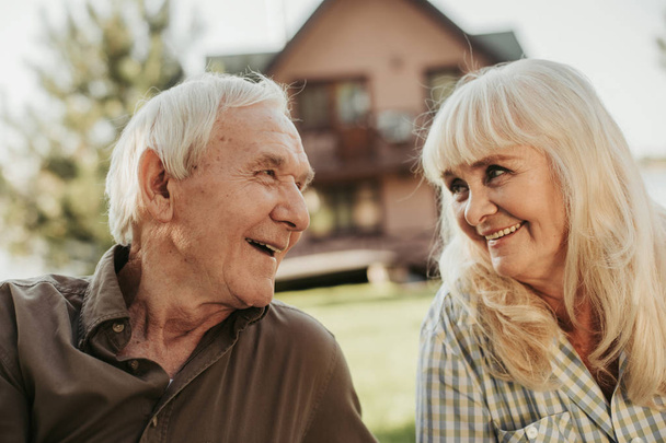 Happy old couple sitting at lawn fronting house - Photo, Image