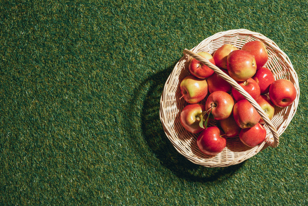 manzanas rojas en canasta de mimbre sobre fondo de hierba
 - Foto, Imagen