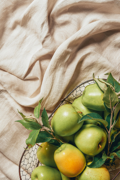 top view of green apples in metal basket on sacking cloth - Fotografie, Obrázek