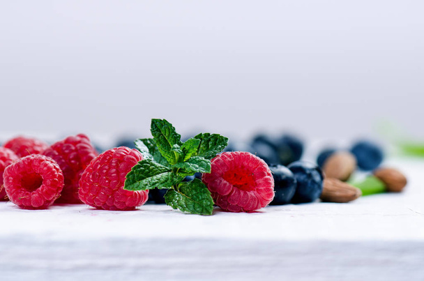 Blueberry, spinachy and orange smoothie on a wooden white background. Glasses of smoothie with berry and mint. Berry, leaf and lime, raspberries on a table. Fruit Healthy food. Breakfast. - Φωτογραφία, εικόνα