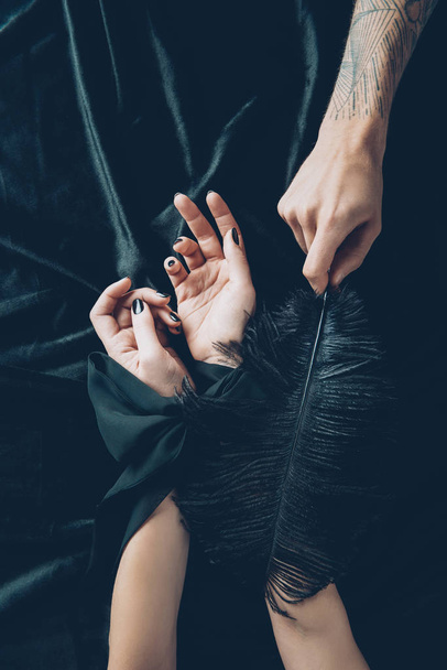 atış bağlı eller ve siyah tüy tutan adam kadının kırpılmış - Fotoğraf, Görsel