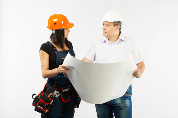Porträt eines männlichen Architekten und einer Bauarbeiterin bei der Diskussion eines Bauplans. Polier mit Papierrollen - Foto, Bild