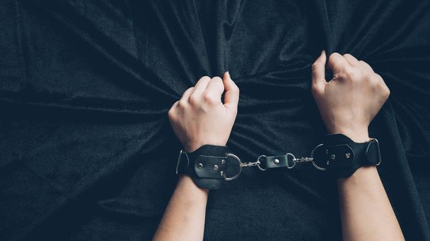 partial view of woman in leather handcuffs holding black fabric - Photo, Image