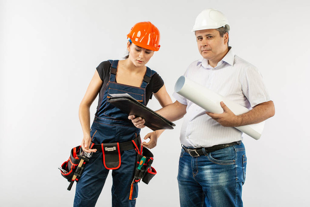 bouwers in veiligheidshelm of helm bespreken blauwdrukken met tablet - Foto, afbeelding