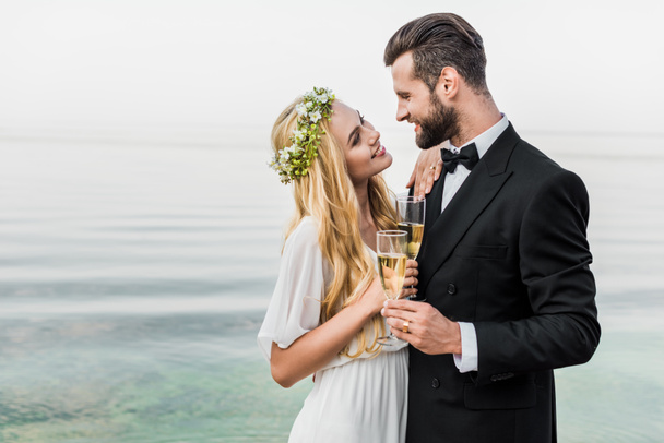 ślub pary gospodarstwa okulary szampana i patrząc na siebie na plaży - Zdjęcie, obraz