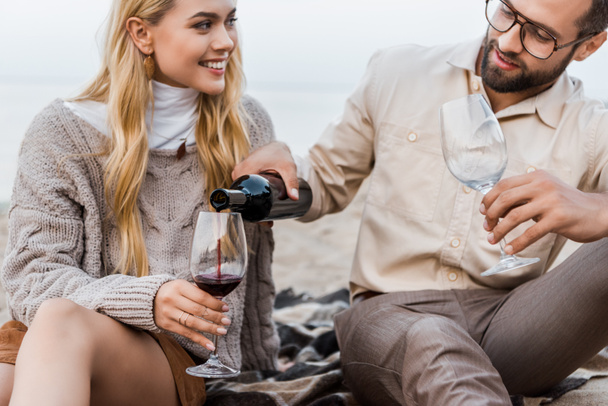 petit ami en tenue d'automne verser du vin rouge dans des verres sur la plage
 - Photo, image