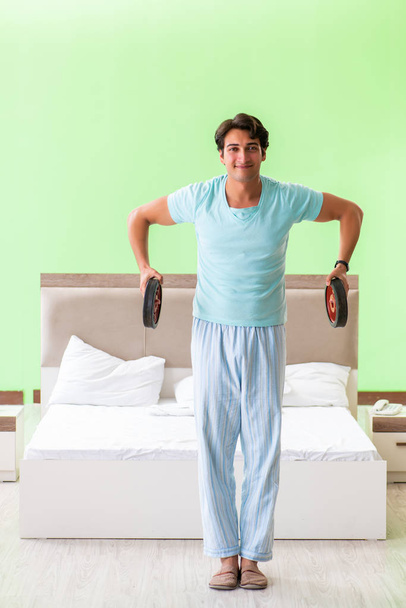 Νεαρός με πιτζάμες κάνει πρωινές ασκήσεις  - Φωτογραφία, εικόνα