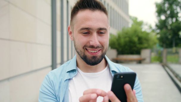 Man with Beard Using a Phone in Town - Photo, Image