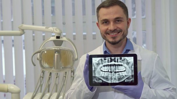 Дантист демонстрирует рентген человеческих зубов на планшете
 - Фото, изображение
