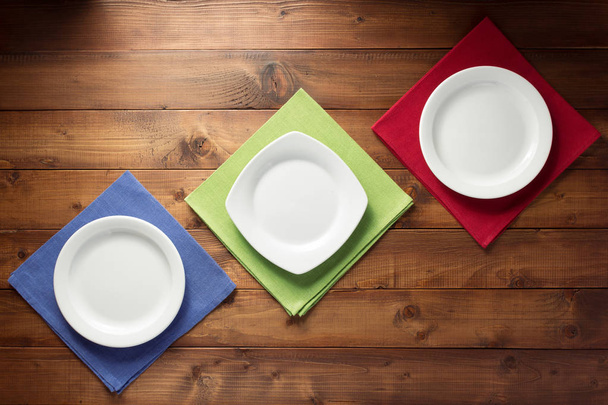 plate and napkin cloth at wooden table background, top view - Zdjęcie, obraz