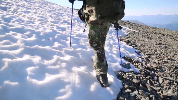 Turisti kävelee lumen peittämää polkua.Mies kävelee lumessa vaelluksella korkeilla vuorilla
. - Materiaali, video