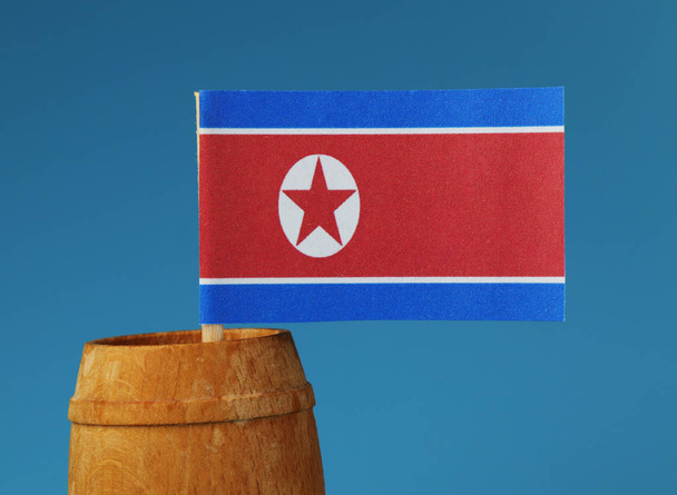 Egy részlet a papír Észak-korea zászlaja fából készült botot fahordós érlelés. Kék háttér - Fotó, kép
