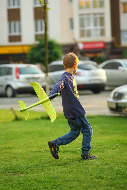 Chico jugando con un avión de juguete en el césped al aire libre
 - Foto, Imagen